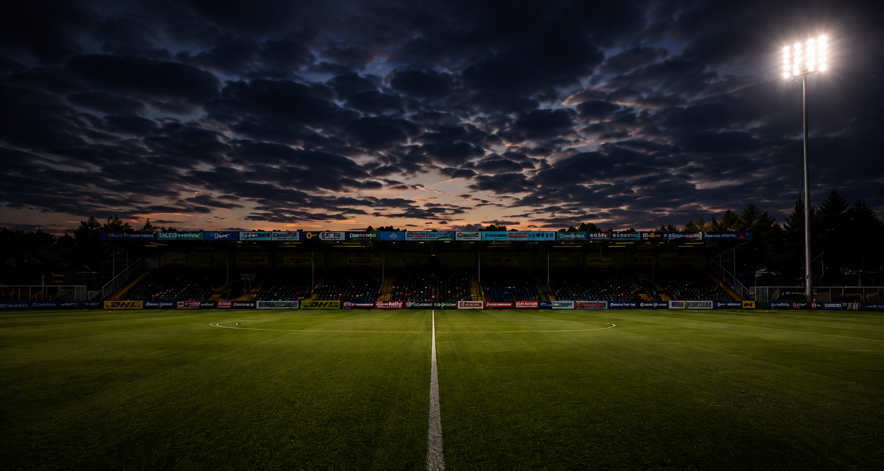 Floodlit football pitch beneath a dramatic evening sky