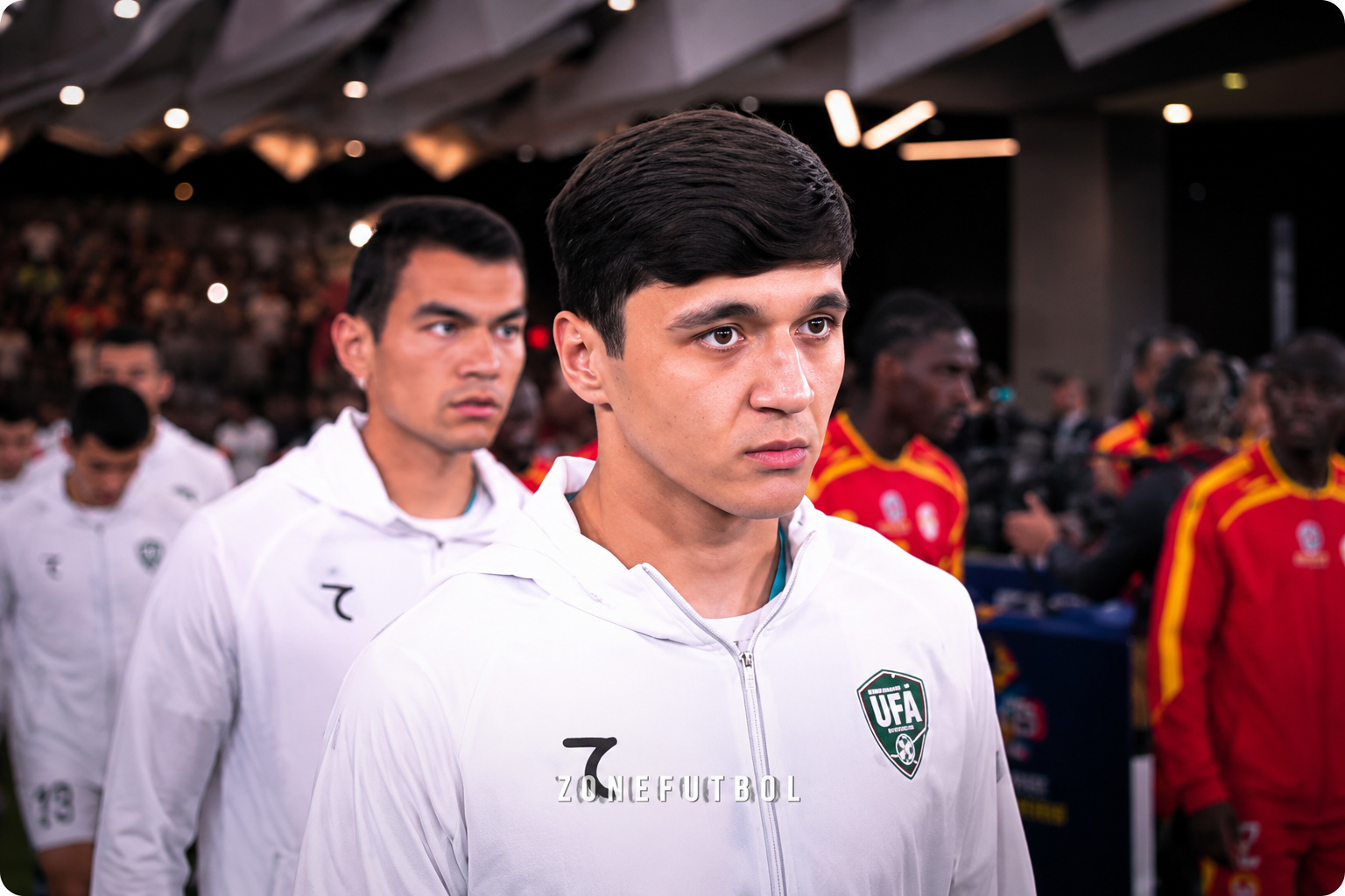 Khusanov walking through the stadium tunnel in an Uzbekistan tracksuit